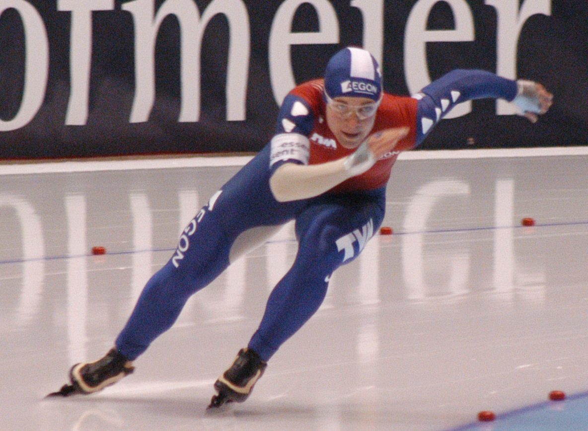 Patineuse de vitesse penchée dans un virage de l'anneau